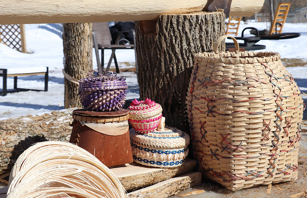 photo 3 three small decorative baskets and one small birch basket stacked on a log. one large basket is to the right of the stack.