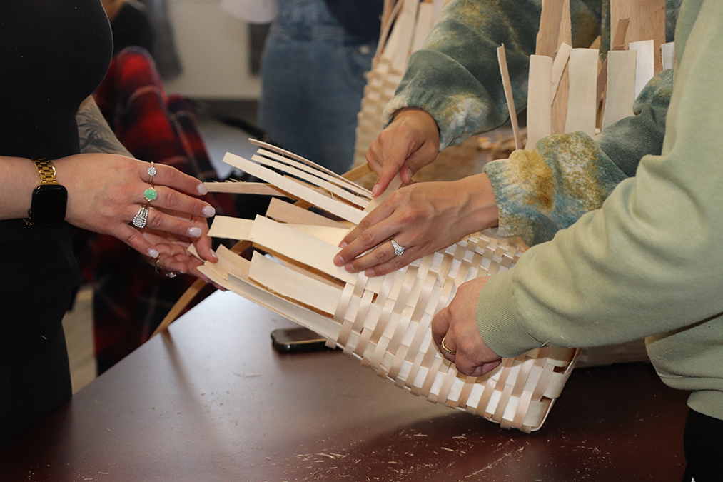 photo 6 Three women work together one a single basket. The photo is a close up of their hands and the basket.