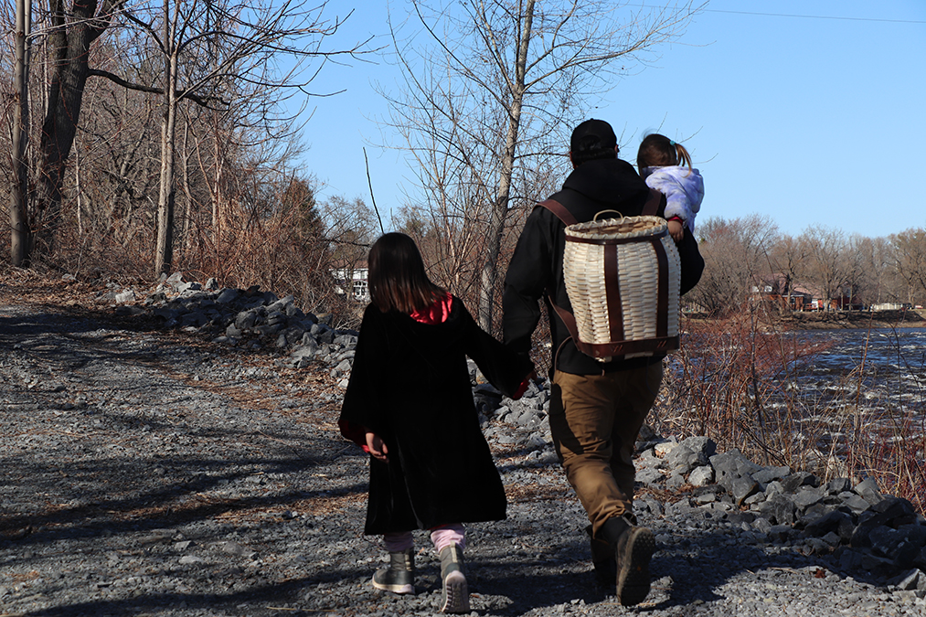 photo 7 Johnson walks along a gravel path in a forest with a basket- backpack holding his oldest daughter Willow's hand. He also carries his youngest daughter Taya.