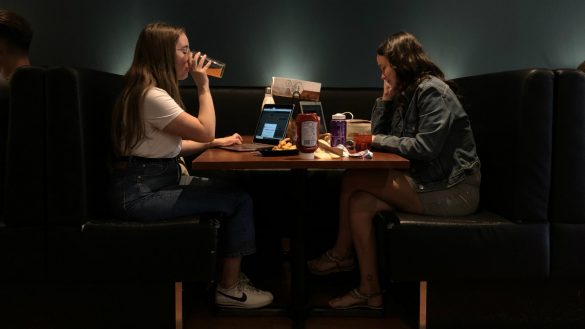 Two women enjoy drinks and food in a restaurant booth