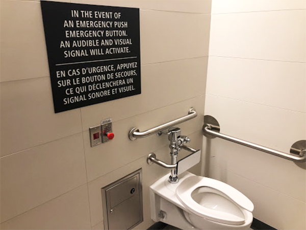 A washroom is shown, with a red emergency button shown, along with a black sign on top indicating its use.