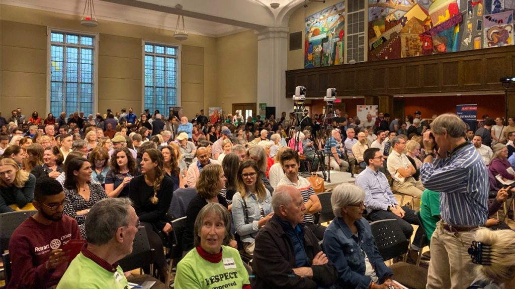 Photo shows a very large crowd in the Glebe Community Centre as they wait for the debate to begin.