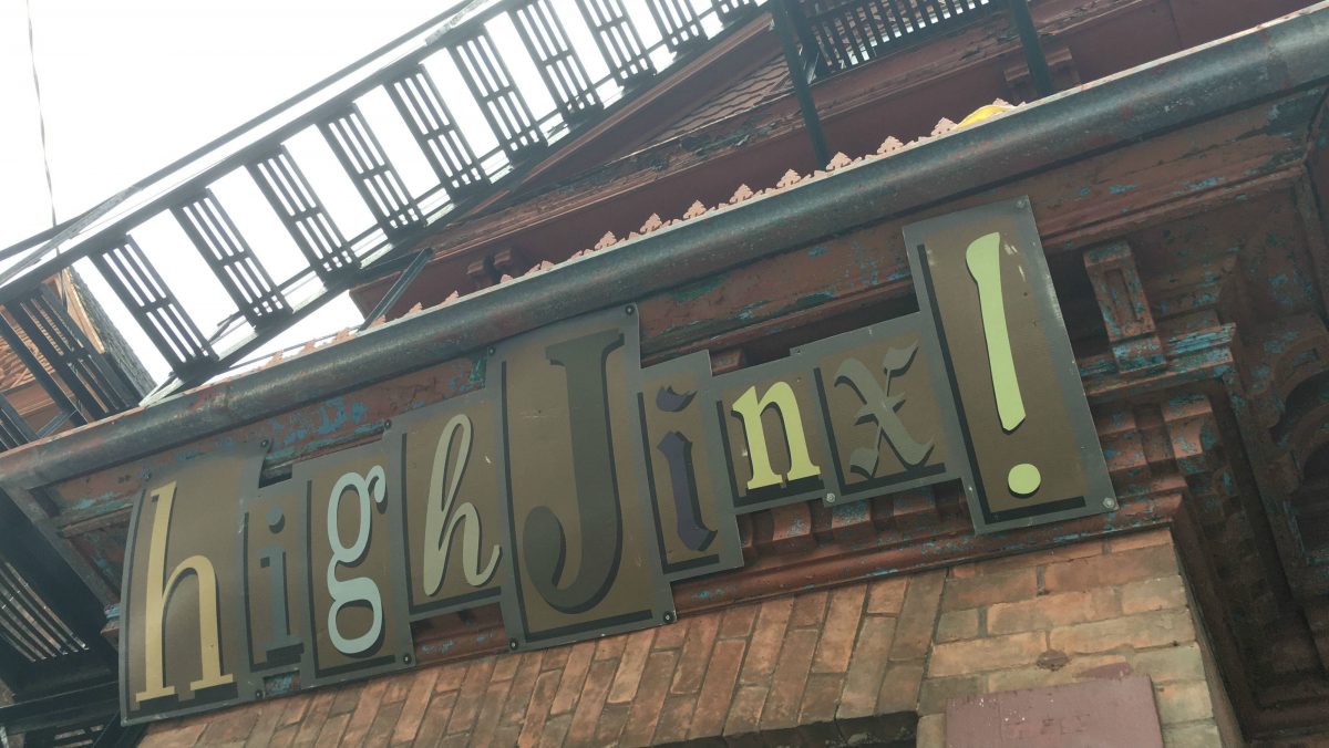 A red brick building with a brown sign  with the word "high Jinx!"