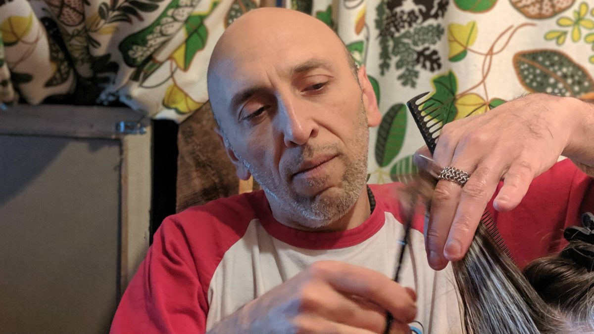 Closeup image of the man focusing on cutting the woman's hair.