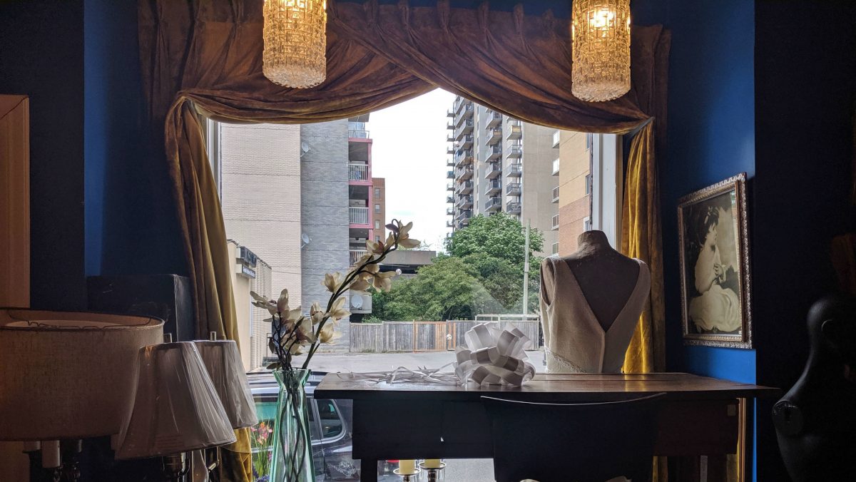 The window display as seen from inside the shop. This angle shows the dark blue walls of the store and the back of the mannequin. 