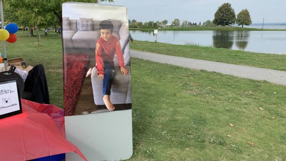 A picture of a young boy plastered on a table in a park on a lake