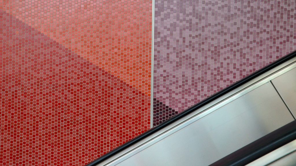 The walls of Tunney's Pasture station feature red and purple tiles near an escalator.