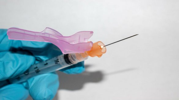 A gloved hand holds a syringe