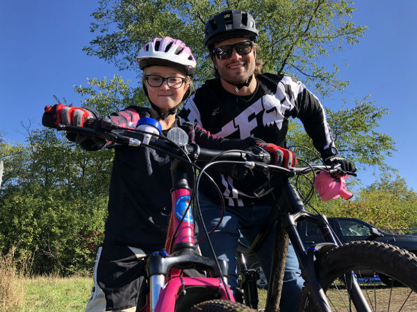 A father and daughter sit on their bikes eagerly waiting for the bike park to open