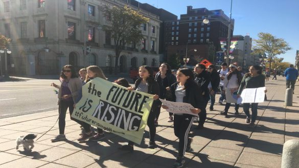 Youth walk down street holding climate change protest signs