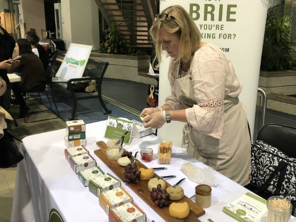 Woman standing at a table serves samples of vegan cashew-based cheese spread during the film festival. 