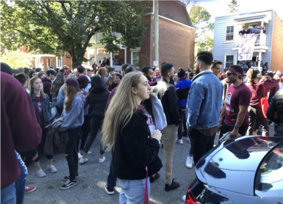 Crowd of students on Russell Street. House with people crowded on balcony in background
