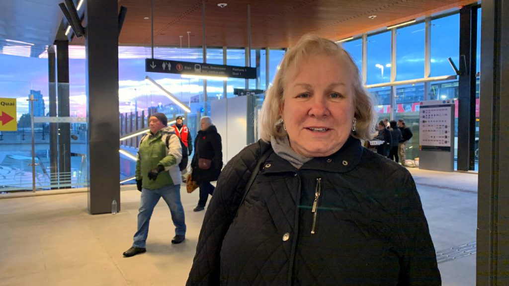 Monica Mahaney stands in the Tunney's Pasture station as the sun sets behind her. 