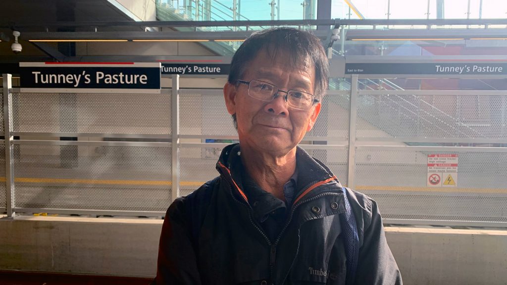 David Siu stands on the platform waiting for the LRT at Tunney's Pasture station.