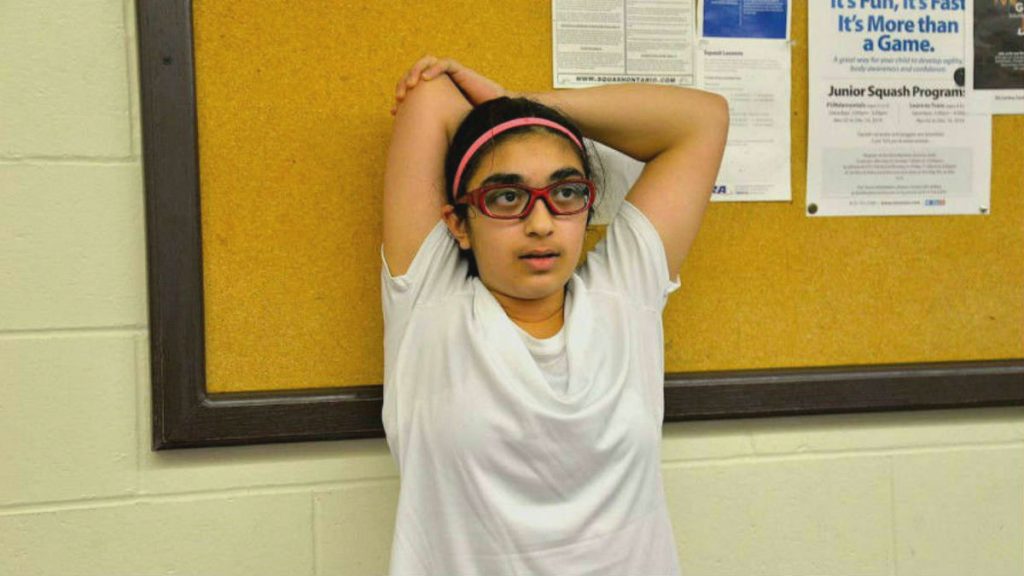 Girl in white t-shirt stretches her arm behind her head.