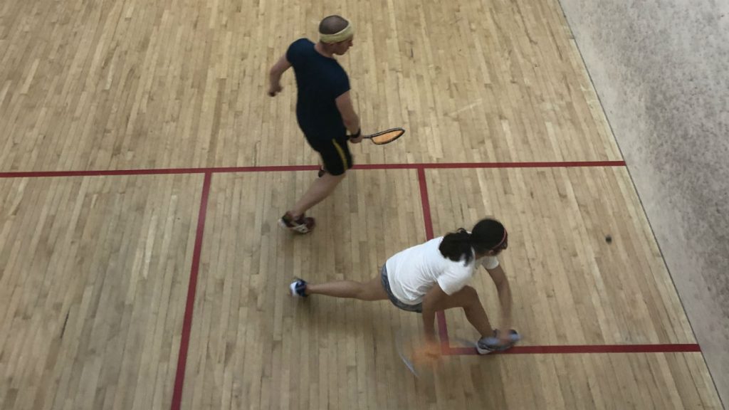 athlete dives to get the ball, racket blurred by the motion and lunging to make the shot.