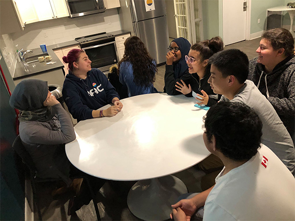 A group of children are seated around a table as they chat during a NROCRC youth night.