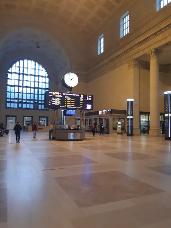 Union station empty. In the centre is the help desk and departure/arrival sign.