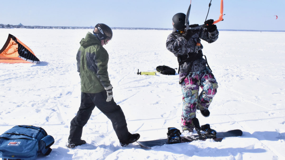 As a friend watches on, Campbell gets into place on his snowboard while holding onto his kite.