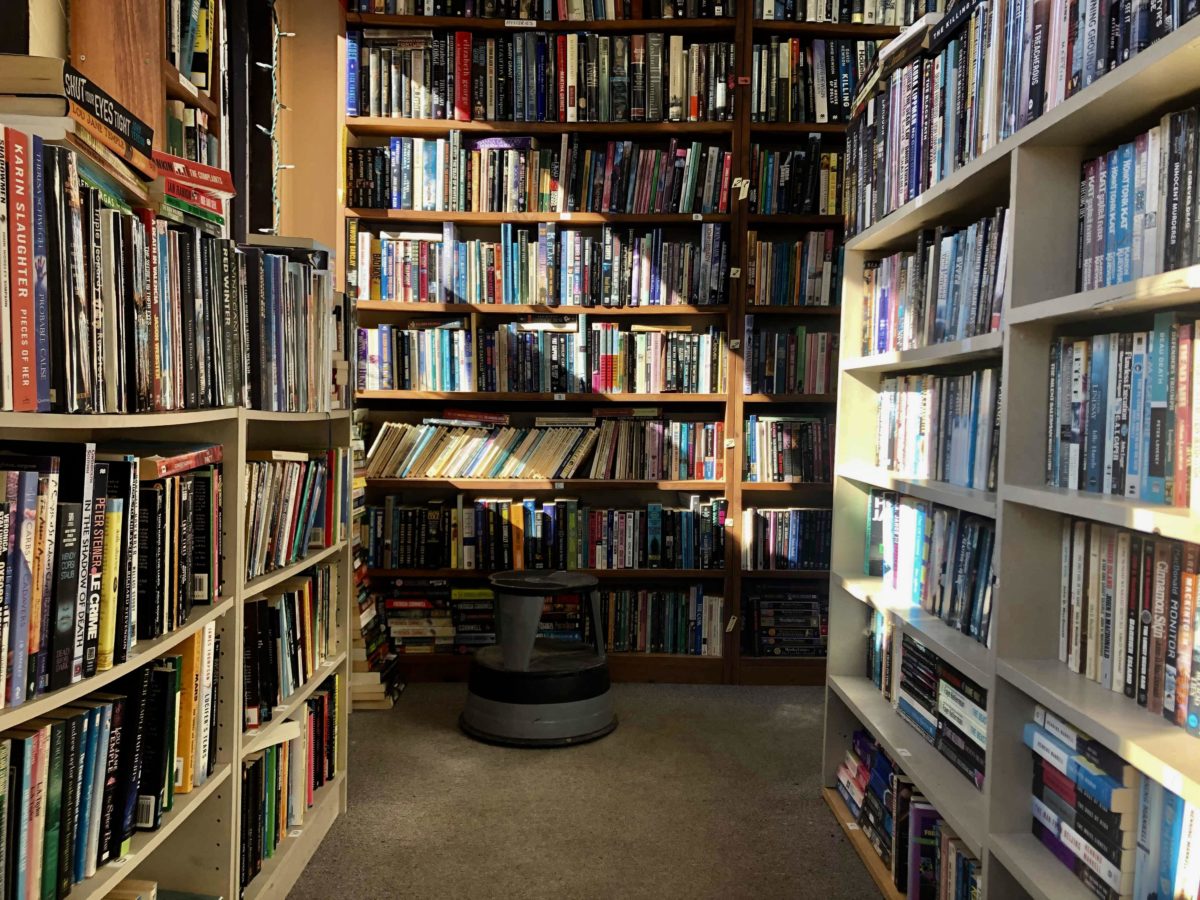 Stacks of books with light shining diagonally across the shelves. Stool in front.