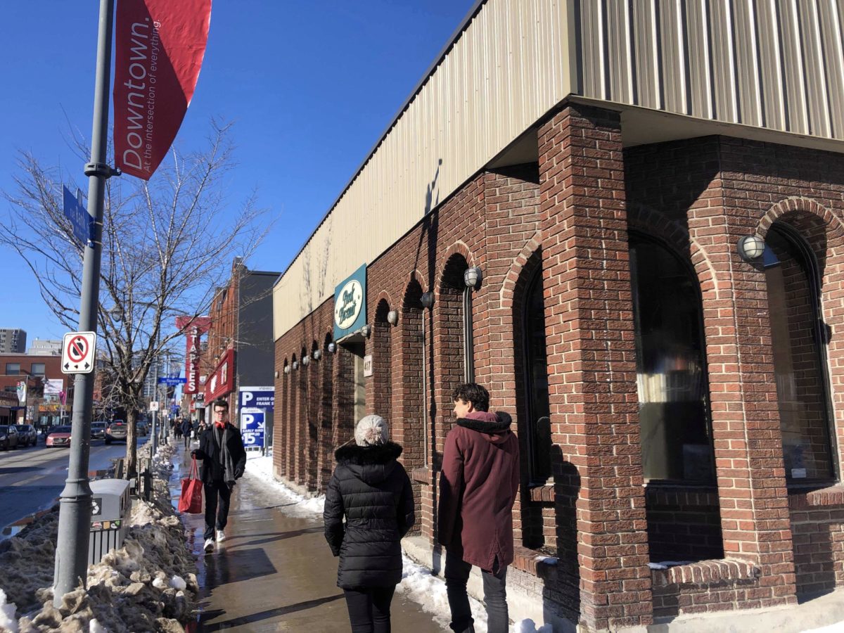 The outside of Book Bazaar. Three people walking by. Snow and slush on sidewalk. 