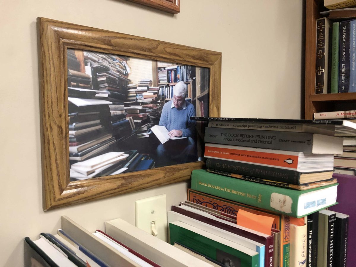 Photo of John Wyatt 30 years ago. Reading a book amongst stacks of other books.  