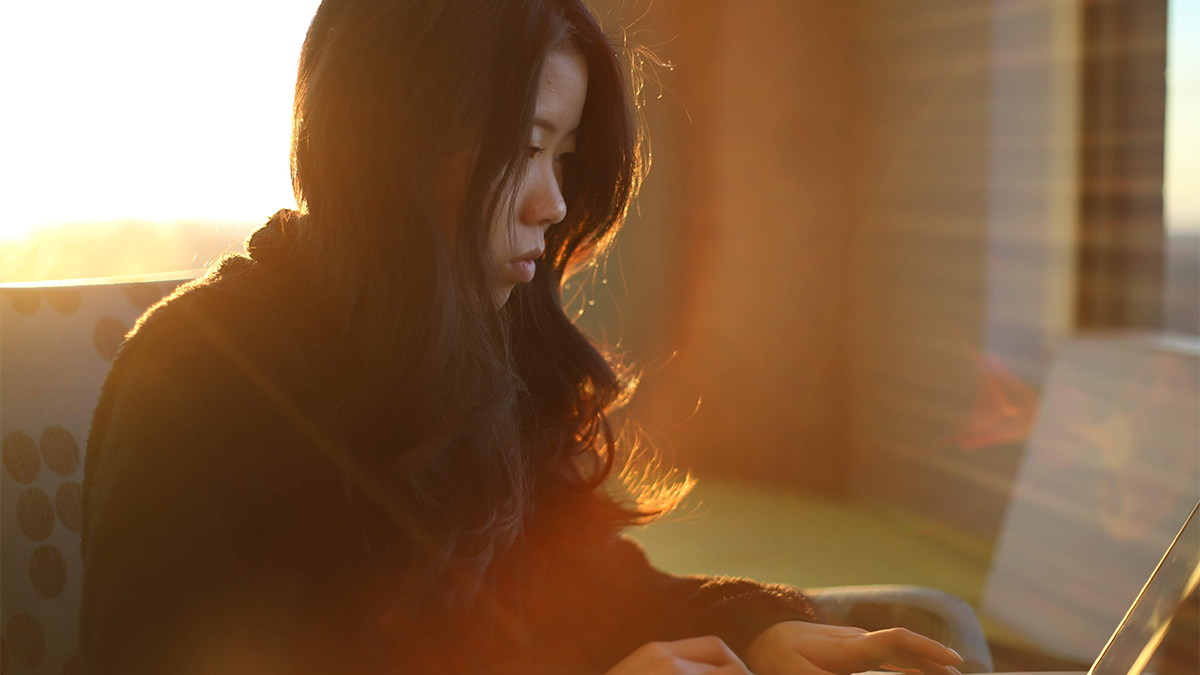 A student sits as she works on her laptop.