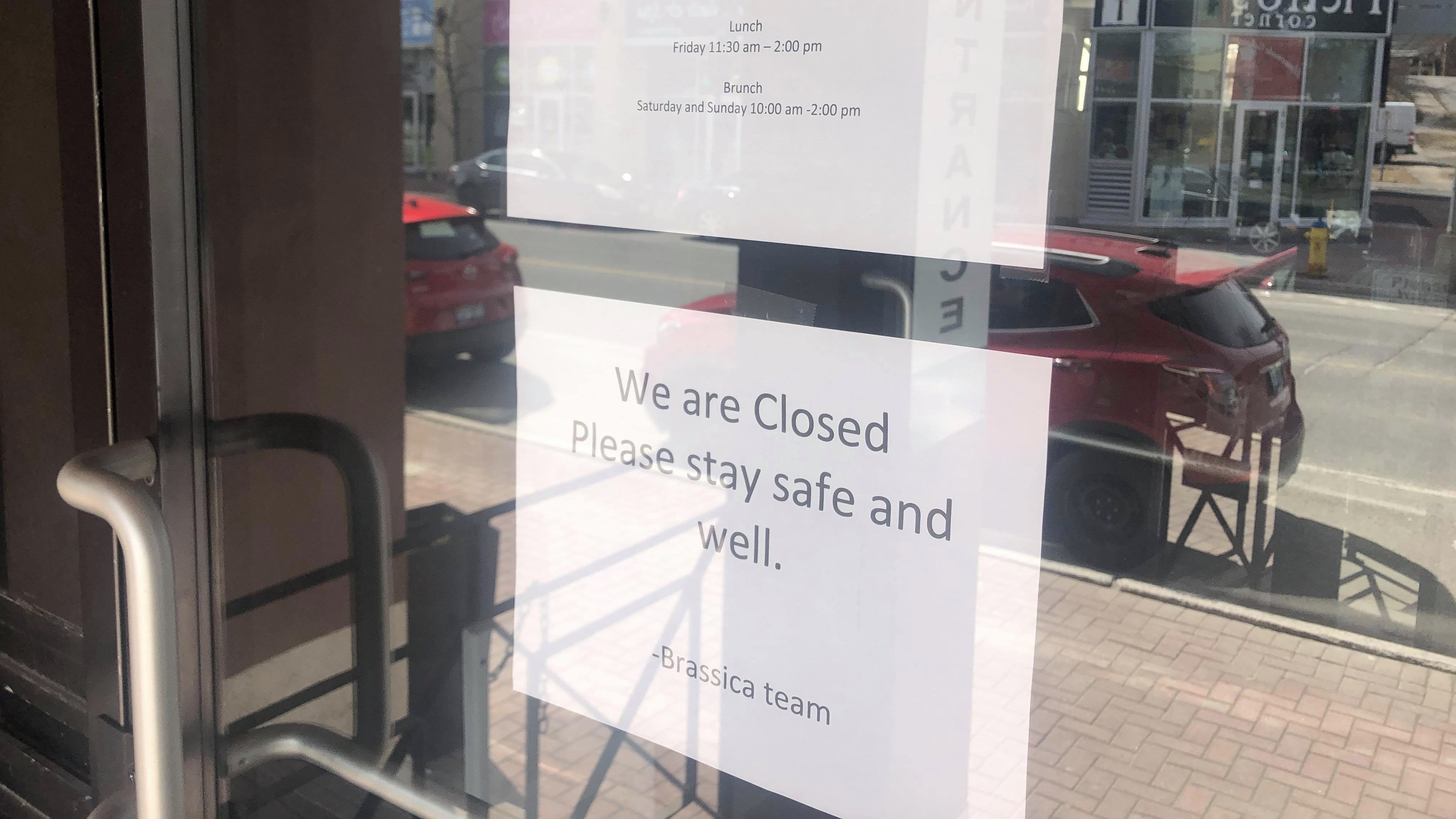 Front door of Brassica. Notice saying "We are closed. Please stay safe and well. - Brassica Team." 