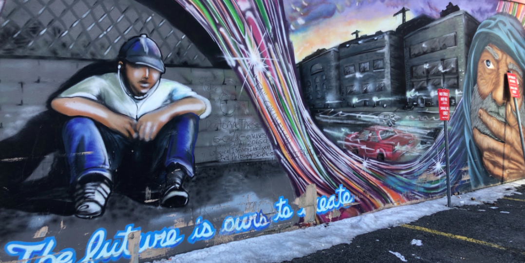 A mural on a building wall in a downtown Ottawa parking lot shows a young homeless man and an older homeless man.