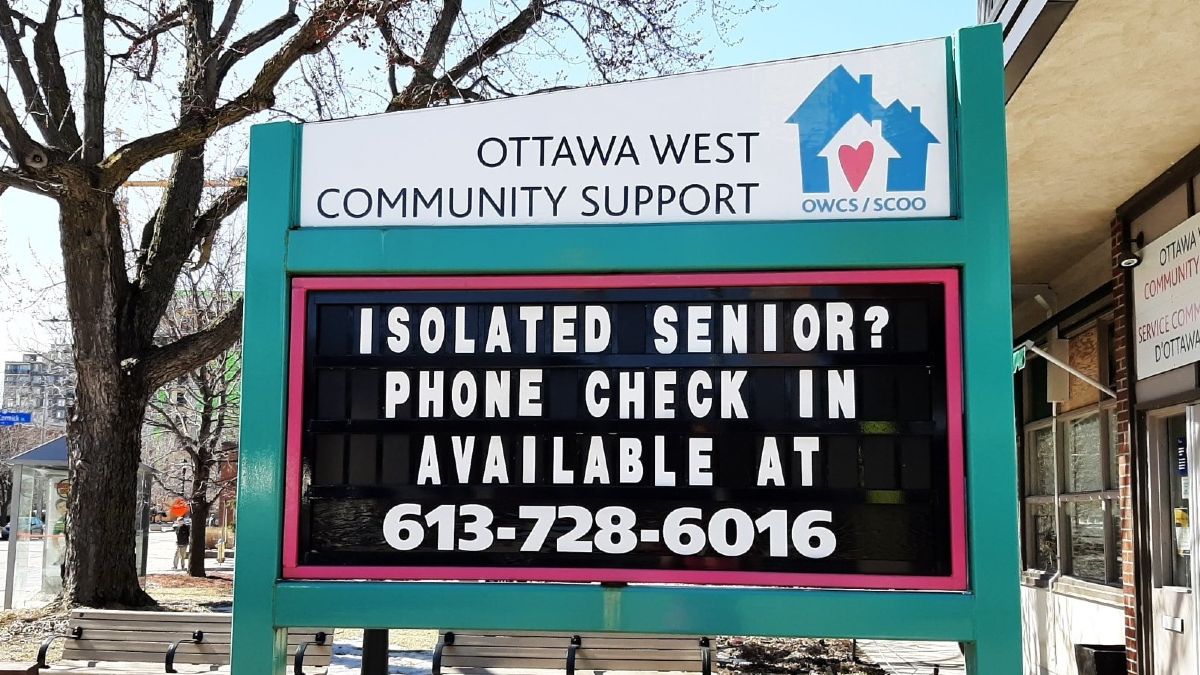 A sign in front of a community centre for seniors gives a phone number for seniors to call if they are isolated during the pandemic.