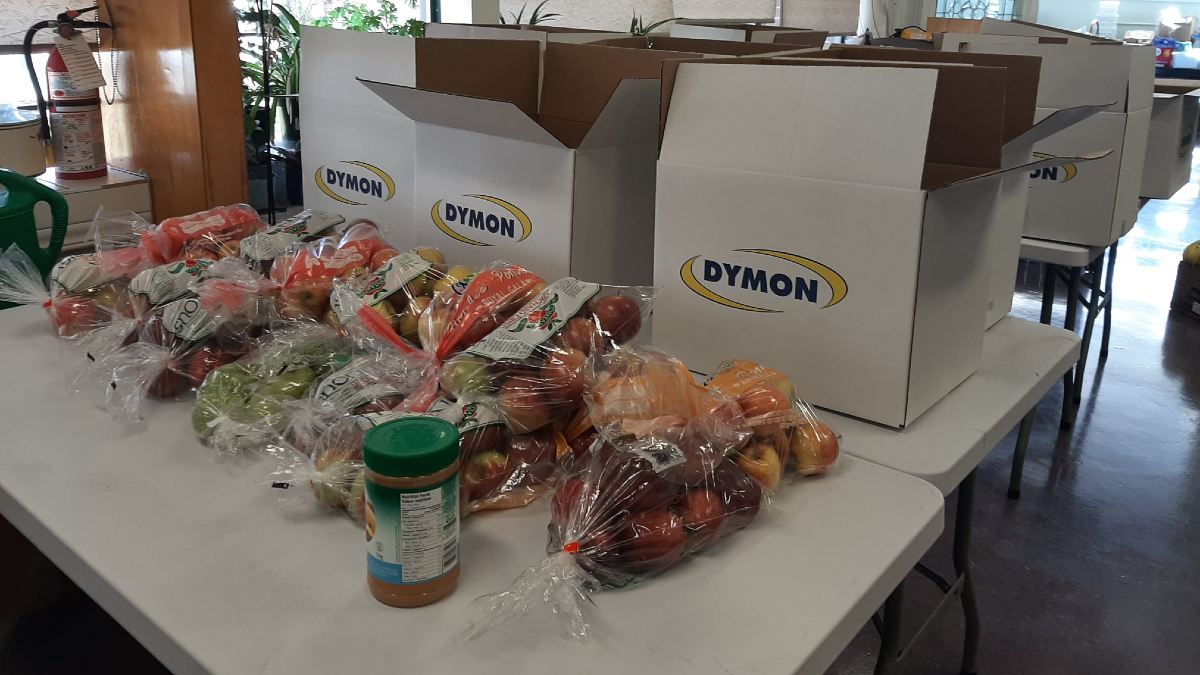 Peanut butter and bags of fruit on a table being ready to be put in boxes and delivered to seniors who can't leave their homes. 