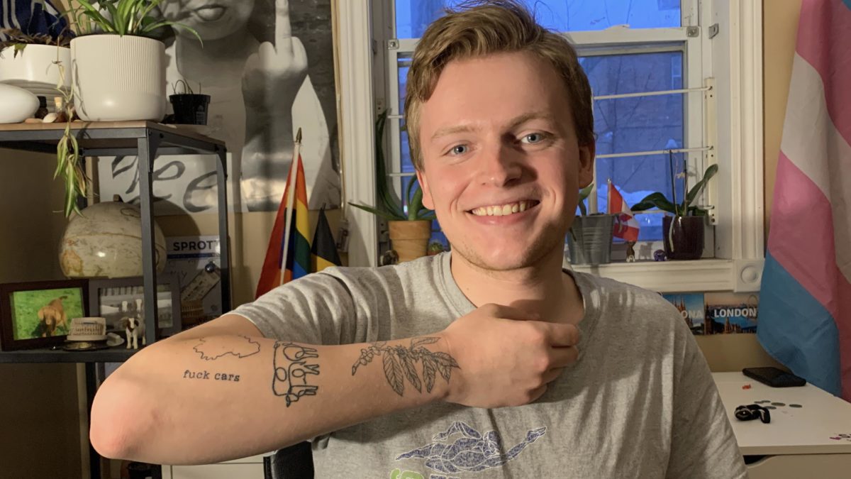 Ward Verschaeve sits in his room with his arm raised to show off his anti-car tattoo.