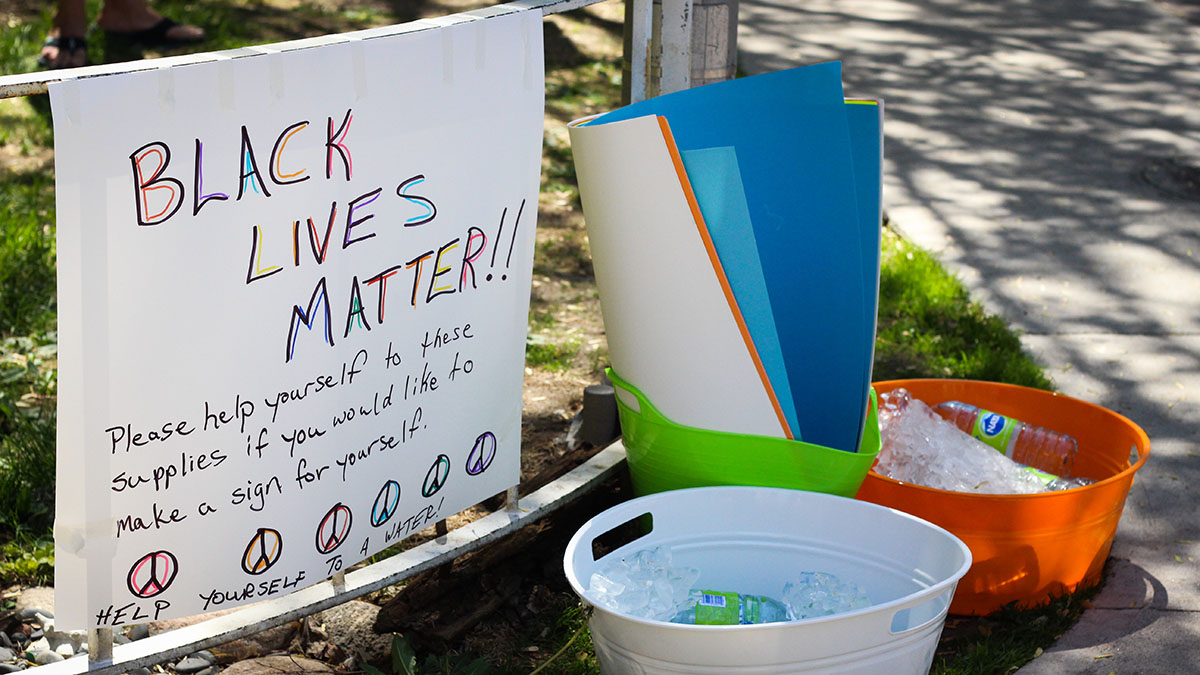 A sign reads "Black lives matter!!" next to buckets filled with water bottles.