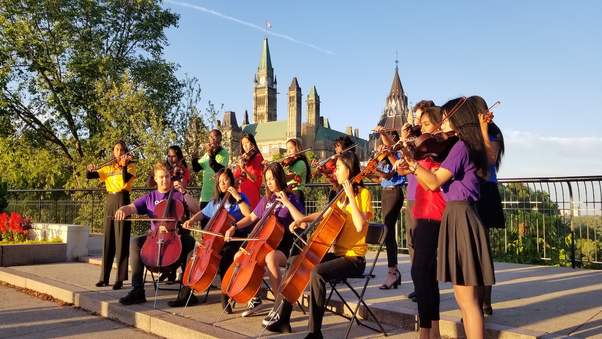 Children from the OrKidstra ensemble play with Parliament Hill in the background