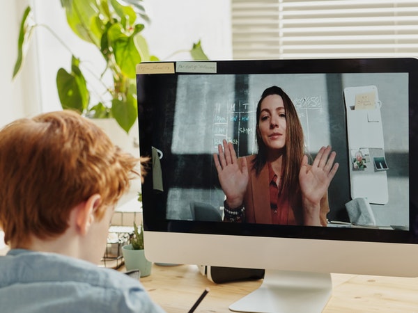 A child is video chatting with his teacher while he is at home.