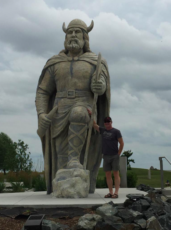 A visitor stands next to the viking statue in Gimli.