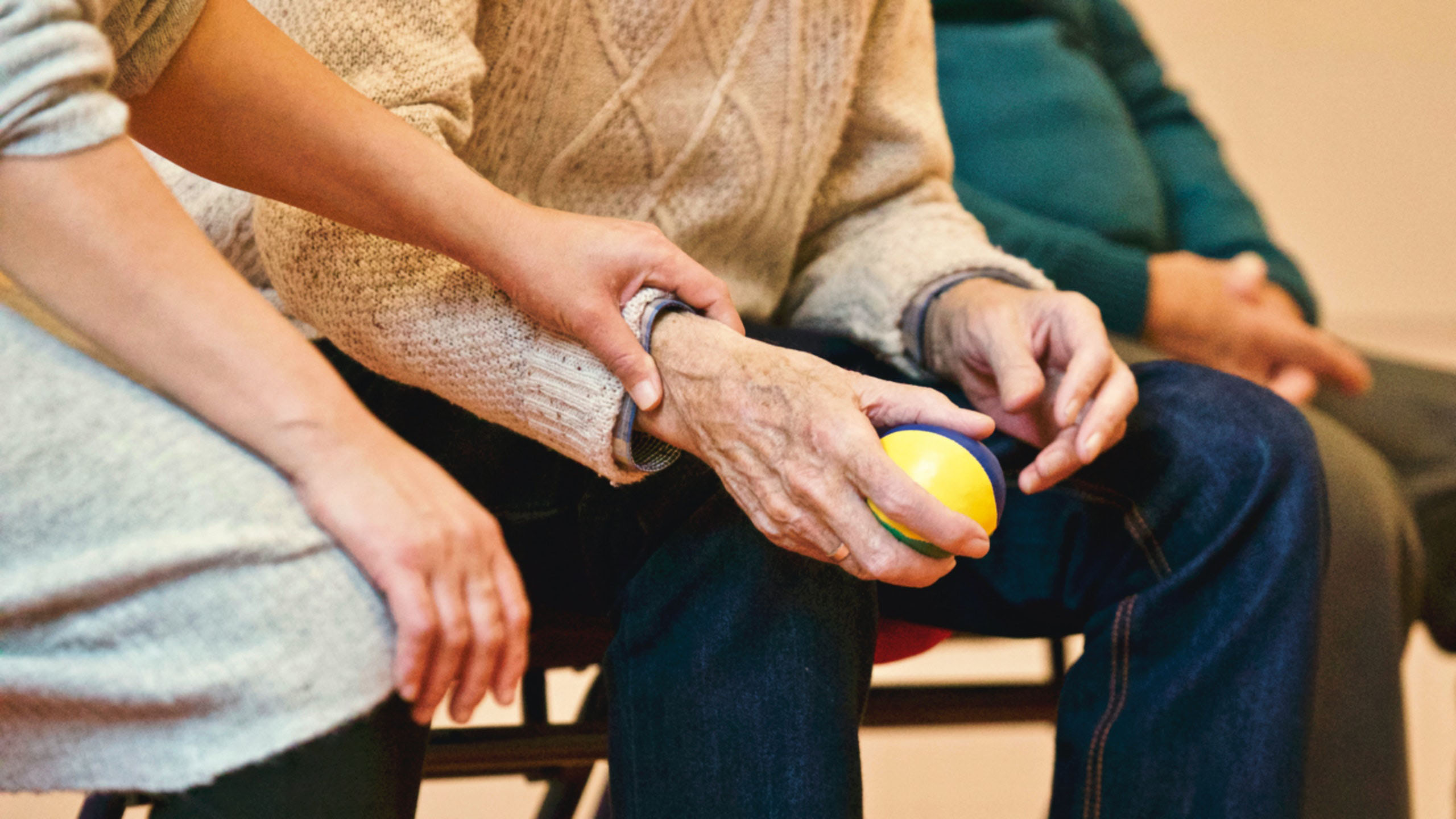 An elderly man holds a stressball.