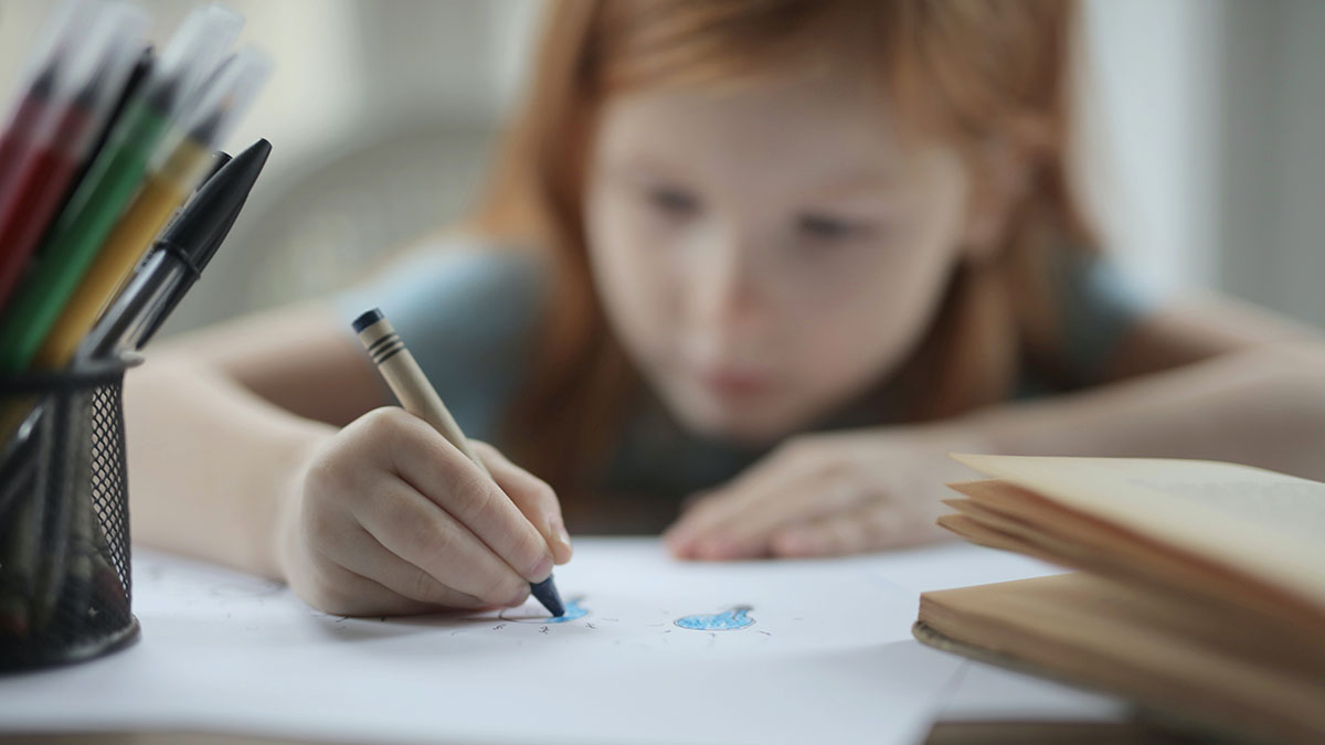 A girl colouring with a crayon.