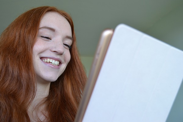 Carleton University student smiling at an iPad. 