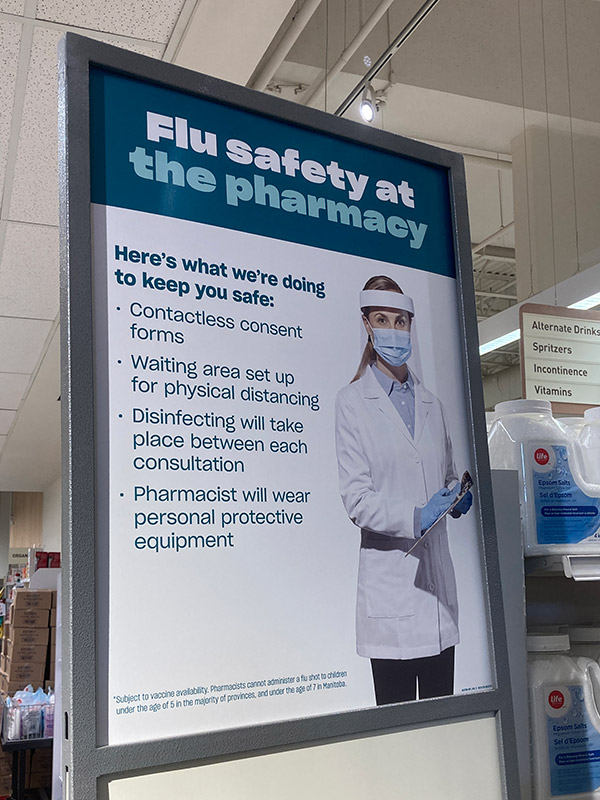 A sign inside a pharmacy that explains what COVID-19 precautions they will be taking, including contactless consent forms, waiting areas for physical distancing, disinfecting and wearing personal protective equipment.