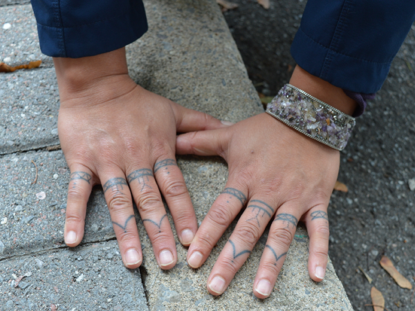 Heidi Langille flattens her hands on a cement curb to show off her traditional Inuit tattoos that her niece did for her using the stick and poke technique. 