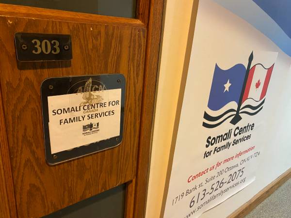 The door of the Somali Centre office, next to a sign with information about the Centre, including a logo and contact information.