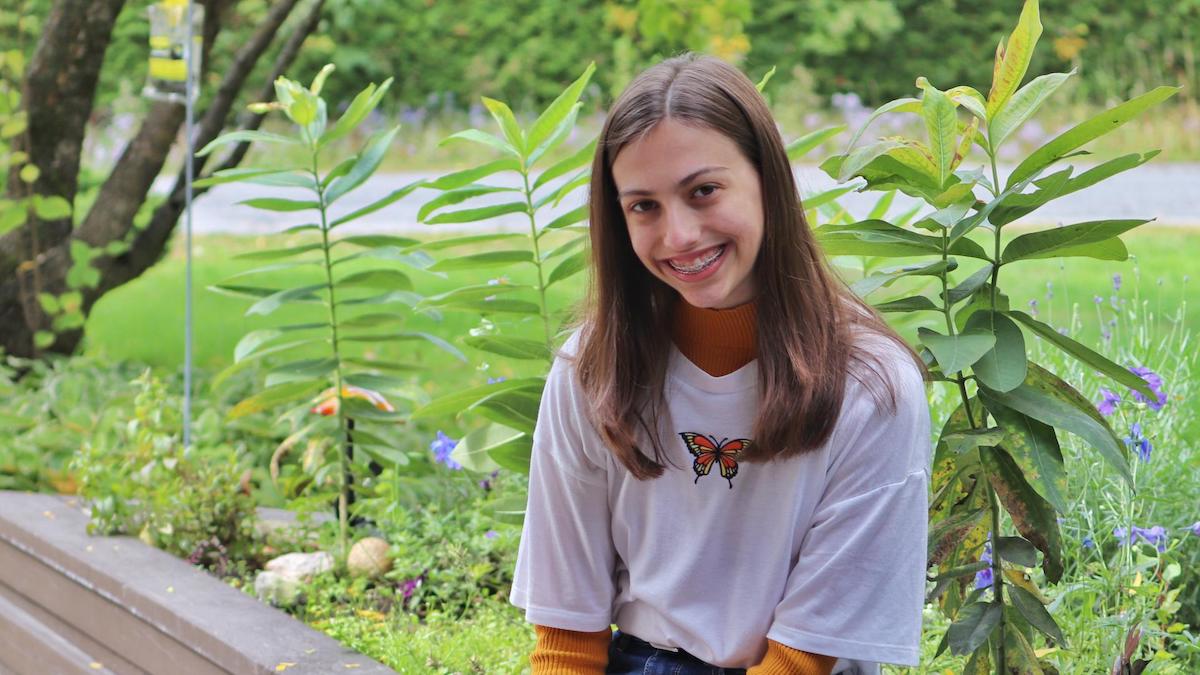 Girl sitting in front of milkweed plants