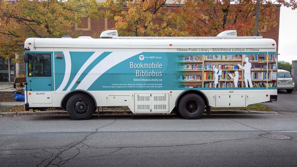 Photo of the Ottawa Public Library's bookmobile (a blue and white bus) parked on the street.