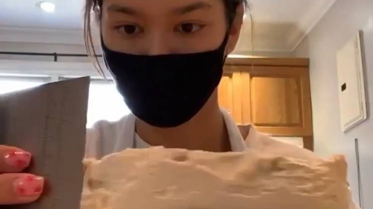 Girl with mask over face ices a cake