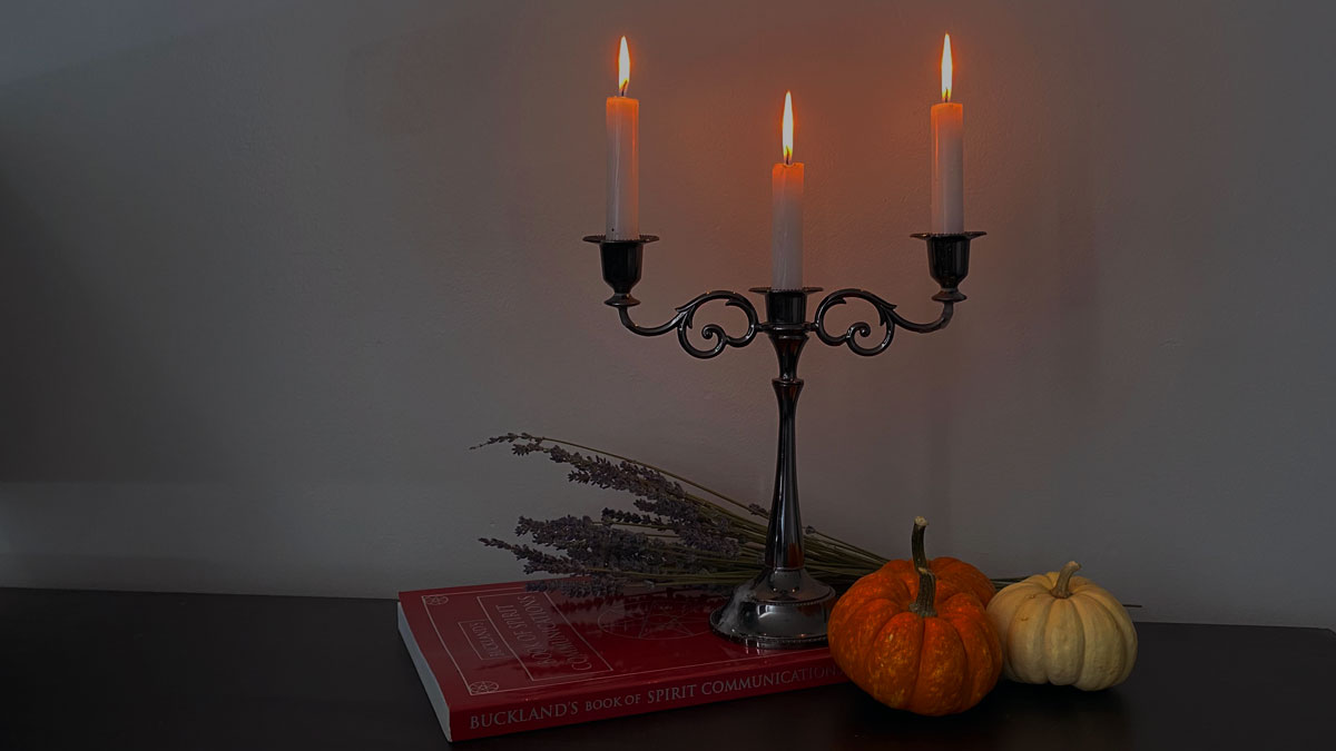 3 tier candles alongside pumpkins, lavender and a book on spirit communication.