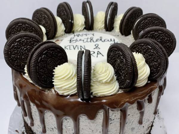 a birthday cake rounded in chocolate drip and Oreo cookies. 