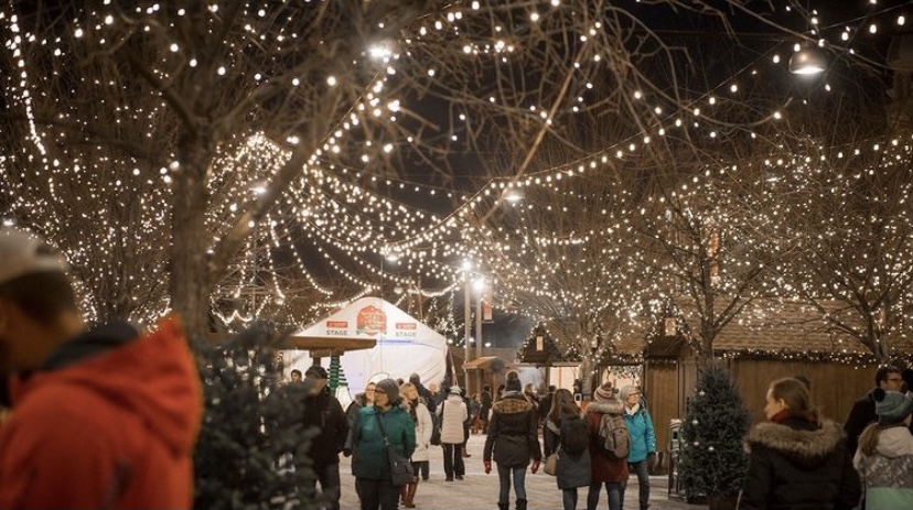 This photo showcases the Ottawa Christmas Market last year, as crowds walk under an array of Christmas lights, passing vendors in wooden huts.