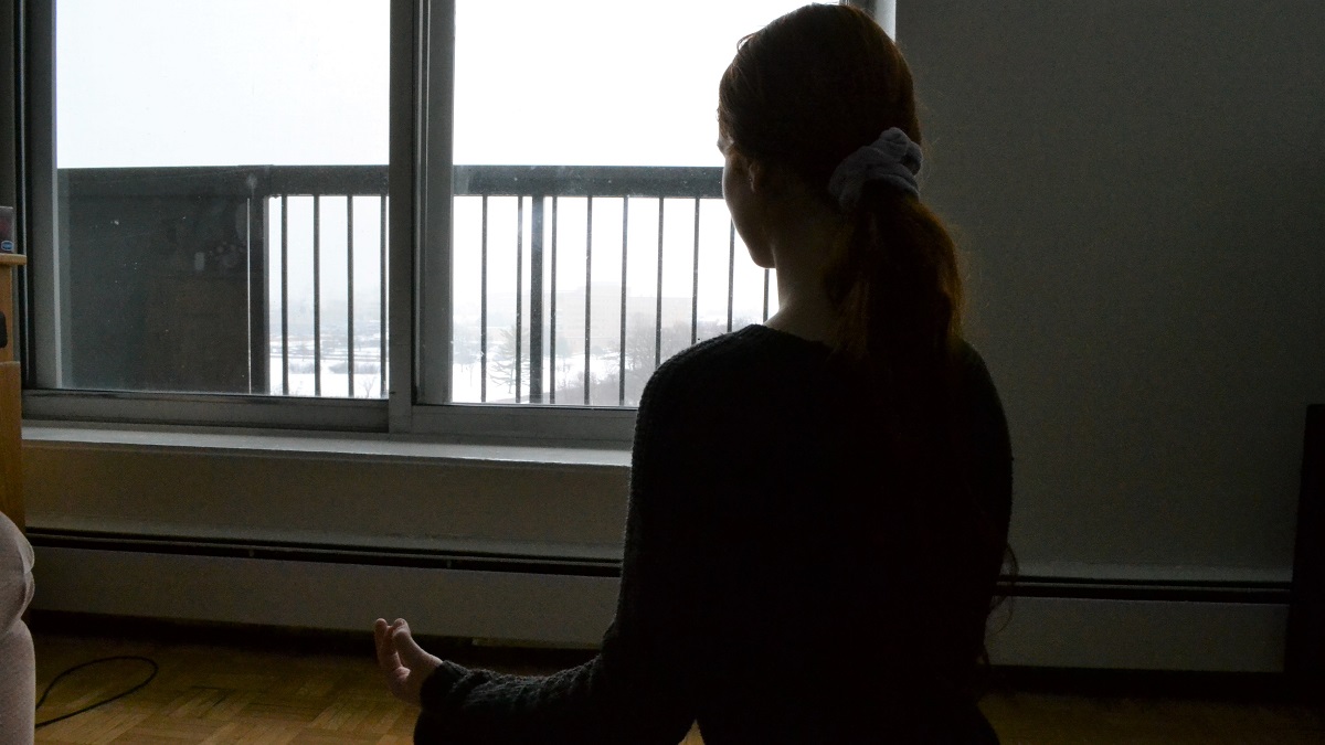 Silhouette of a girl meditating in front of a window.