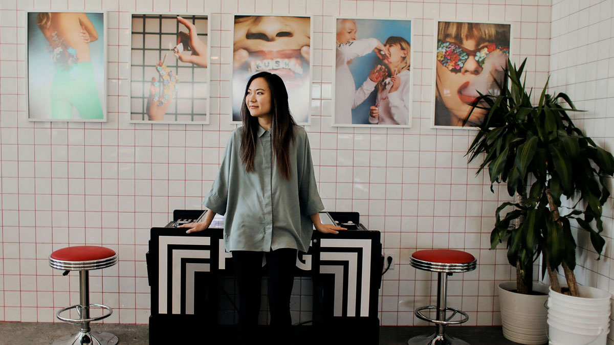 A woman stands in front of a display of cannabis images in a dispensary.